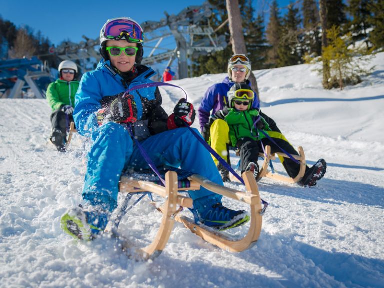 Schlittenfahren und wohnen direkt an der SKipiste Kinder lachen beim Schlittenfahren
